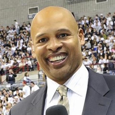Clark Kellogg in a black suit poses a picture.